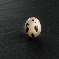 Quail eggs on black stone background. Organic product. photo