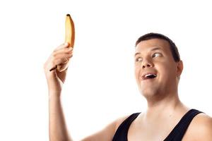 Happy young pleased man looking at the banana. Human emotion, reaction, expression. Isolated on white background. photo