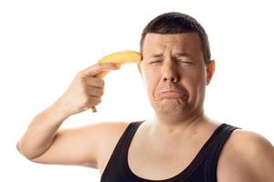 Desperate stressed worried young man with banana directed on his head. photo