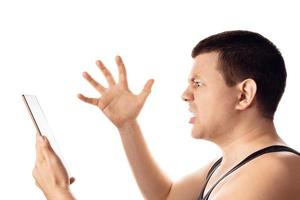 Desperate stressed worried young man reading some bad news from his tablet. Human emotion, reaction, expression. Isolated on white background. photo