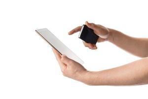 El hombre sostiene el teléfono negro y toca la tableta blanca al mismo tiempo. aislado sobre fondo blanco.