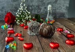 Bodegón romántico chocolate rosa roja en forma de corazones y tortas de chocolate sobre fondo de madera foto