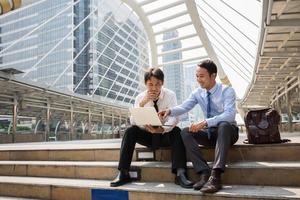 dos hombres de negocios están trabajando con teléfonos inteligentes y portátiles por concepto de negocio. foto