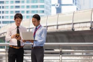 Two businessmen are working on sidewalk with smart phone and notebook for business concept. photo