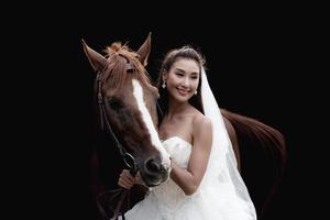 Beautiful bride with horse on black background photo