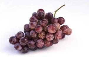 Frutos de uva roja en plato de vidrio aislado sobre fondo blanco. foto