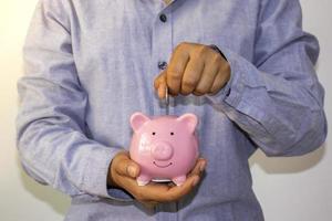 un empresario puso una moneda en una alcancía rosa y guardó el dinero para planificar ideas para futuros fondos de jubilación