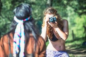 Hippie style girls photograph themselves with vintage camera photo