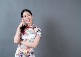 Beautiful young Asian woman wear Chinese traditional dress with hand presenting on side photo