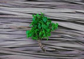 Natural peppermint stalks, bouquet with jute rope binding flat lay on dry palm leaf pattern texture background. Green leafy vegetable with center composition design with space beside, top view style. photo