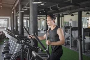 Guapo corriendo en una cinta en un gimnasio foto