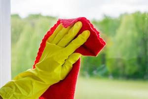 Window washing and home cleaning. Housekeeper in gloves washes and wipes dirty glass. photo