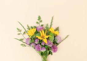 Bouquet from variety of wildflowers on beige background.