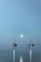 Two boats over the moonlight. Two anchored ships in the open sea under the moonlight, peninsula Kassandra, Greece.