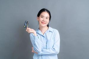 Portrait of a lovely young Asian woman showing credit card photo