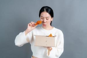 Joven mujer asiática con cara feliz y disfruta comiendo pollo frito