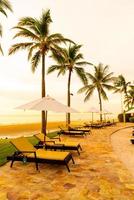 Umbrella and chair around swimming pool in hotel resort with sunrise in morning photo