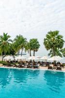 Empty beach chair with umbrella around swimming pool photo