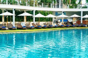 Empty beach chair with umbrella around swimming pool photo