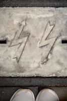 Zigzag thunderbolts embossed in gray concrete with visible feet standing on pavement photo