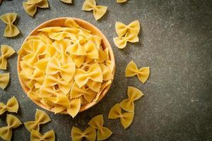 Dry uncooked farfalle pasta in wooden bowl photo