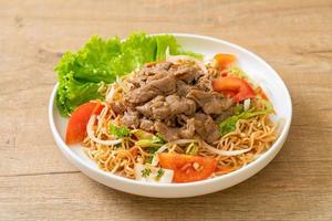 Instant noodle spicy salad with pork on a white plate - Asian food style