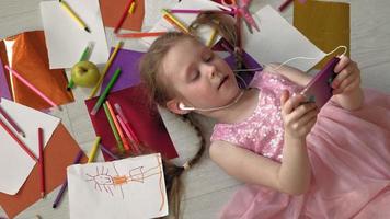 menina deitada no chão ouvindo música no telefone