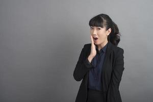 Smiling business woman in blazer on grey background photo