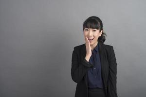 Smiling business woman in blazer on grey background photo