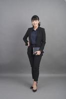 Smiling business woman in blazer on grey background photo