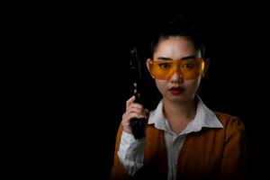 Retrato hermosa mujer asiática vistiendo un traje amarillo con una mano sosteniendo la pistola en el fondo negro