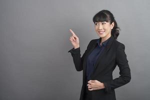 Smiling business woman in blazer on grey background