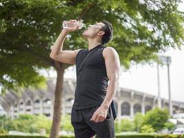 Sport man Drinking water at outdoor city photo