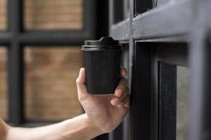 mano humana sosteniendo una taza de papel de café, bebida de la mañana foto