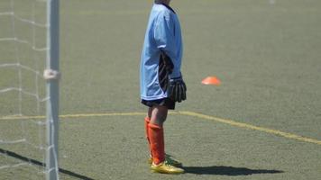 menino jogando goleiro em um jogo da liga de futebol juvenil. video
