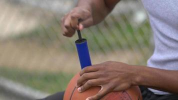 ein junger Mann-Basketball-Spieler, der Basketball aufbläst. video
