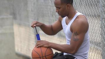een jonge man basketbalspeler die basketbal opblaast. video