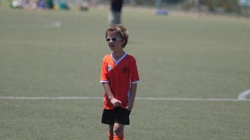 jeune garçon en uniforme orange jouant dans un match de la ligue de football des jeunes. video