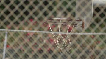 een jonge man basketbalspeler die op een oude basketbalring buiten dompelt.