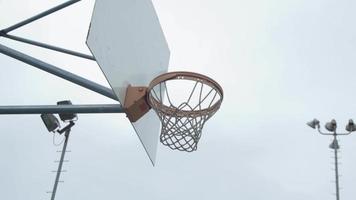 un joven jugador de baloncesto sumergirse en una cancha de baloncesto al aire libre. video