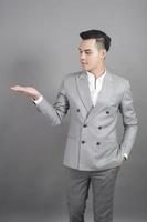 Businessman is showing something portrait in studio grey background photo