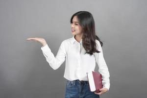 Portrait of woman University student holding book in studio grey background photo