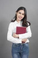 retrato, de, mujer, estudiante universitario, tenencia, libro, en, estudio, fondo gris foto