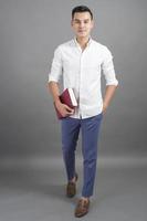 Portrait of man University student holding book in studio grey background photo