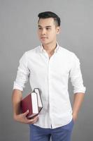 Portrait of man University student holding book in studio grey background photo