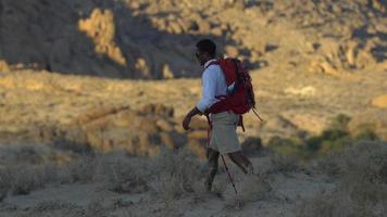 un jeune homme faisant de la randonnée dans un désert montagneux.