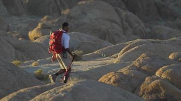 un jeune homme sac à dos sur des rochers dans un désert montagneux.