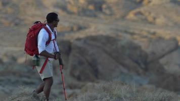 un giovane zaino in spalla in un deserto montuoso. video