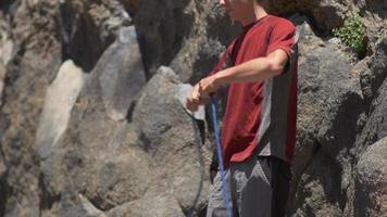 un jeune homme prépare sa corde avant de faire de l'escalade. video