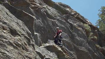 A young man rock climbing on a mountain.